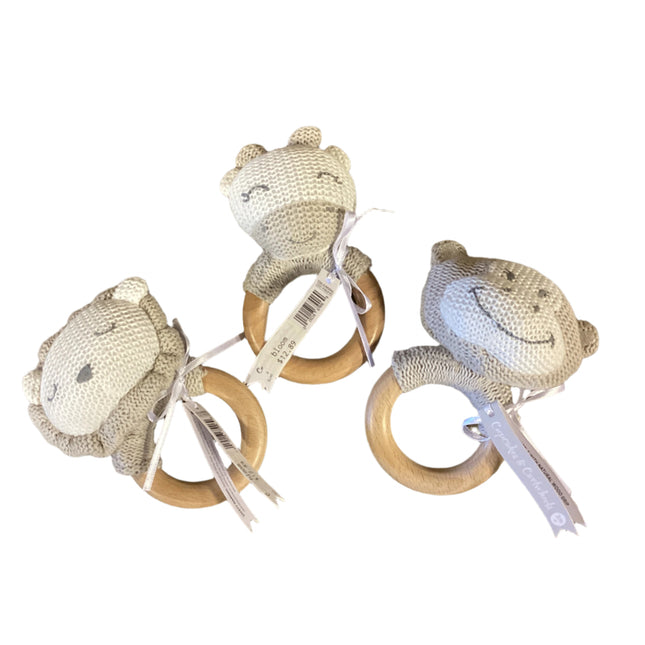 Three baby teething rings with knitted animal heads on a wooden surface