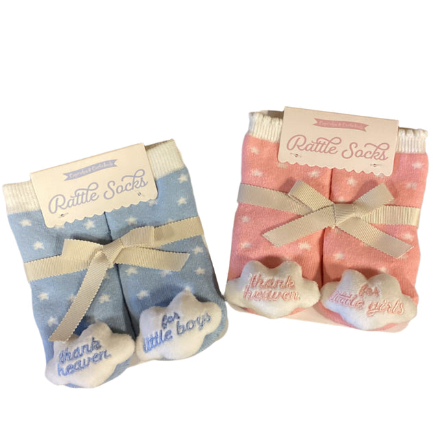 Pair of baby rattle socks with pink and blue designs on a wooden surface